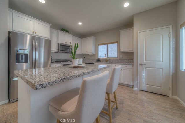 32593 Cumulus Ln, Winchester, CA 92596 - kitchen with appliances with stainless steel finishes, a kitchen island, white cabinets, recessed lighting, and light wood-type flooring