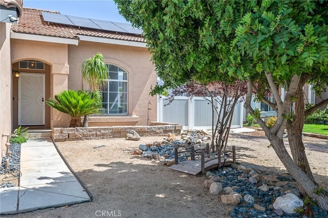 13492 Palomino Creek Dr, Corona, CA 92883 - view of exterior entry with stucco siding, a tile roof, and solar panels