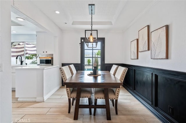 13492 Palomino Creek Dr, Corona, CA 92883 - dining room featuring a tray ceiling, plenty of natural light, light wood-style floors, ornamental molding, and a wainscoted wall