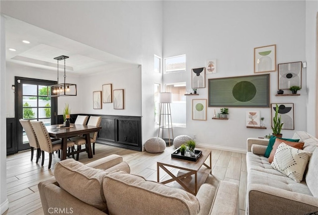 13492 Palomino Creek Dr, Corona, CA 92883 - living area with light wood-style floors, a chandelier, a towering ceiling, a tray ceiling, and recessed lighting