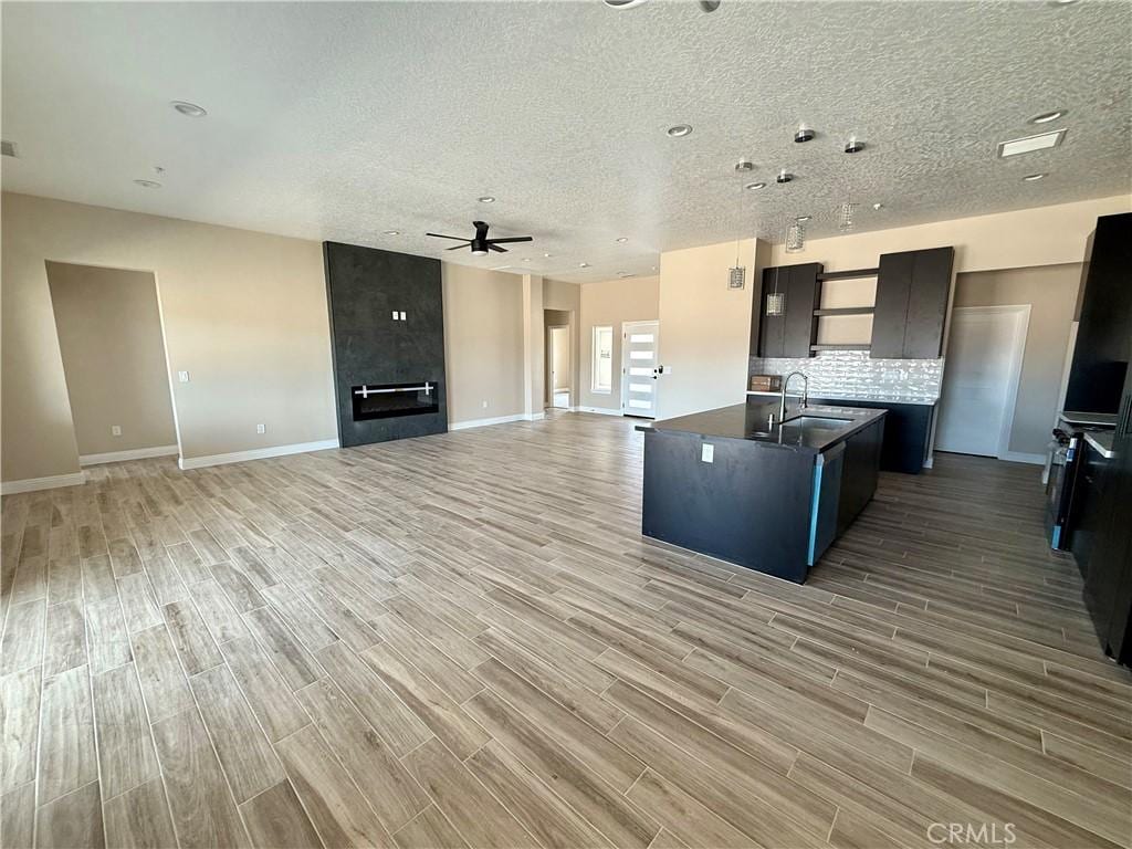 15640 Cheyenne Rd, Apple Valley, CA 92307 - kitchen with ceiling fan, open floor plan, light wood-style flooring, dark countertops, and a textured ceiling