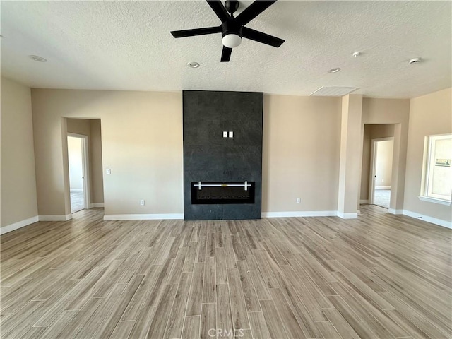15640 Cheyenne Rd, Apple Valley, CA 92307 - unfurnished living room with light wood-type flooring, a textured ceiling, a ceiling fan, baseboards, and a tiled fireplace