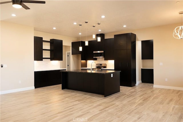 15640 Cheyenne Rd, Apple Valley, CA 92307 - kitchen with stainless steel appliances, dark cabinetry, light wood finished floors, a kitchen island with sink, and tasteful backsplash