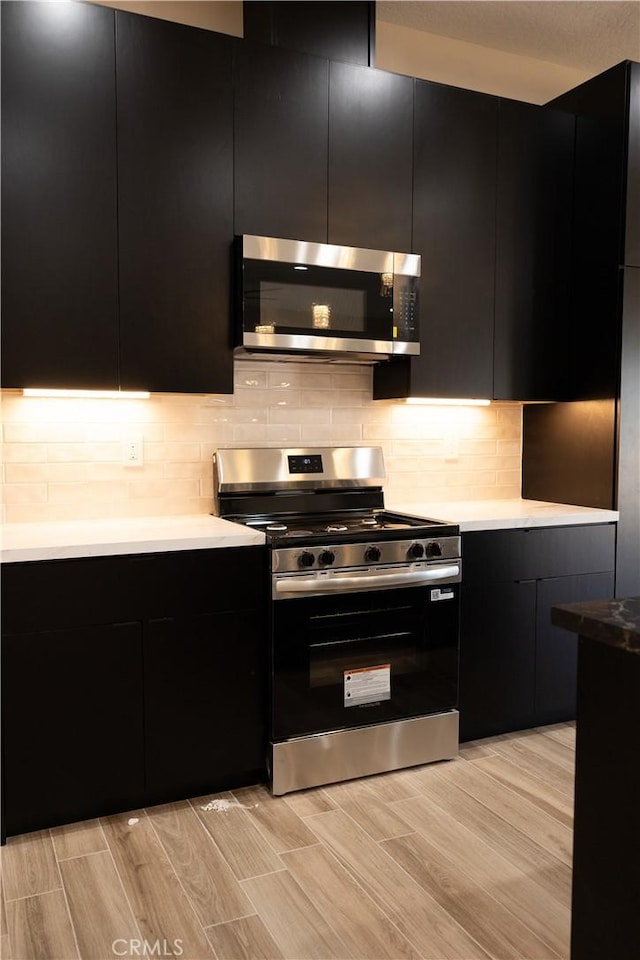 15640 Cheyenne Rd, Apple Valley, CA 92307 - kitchen featuring stainless steel appliances, dark cabinets, modern cabinets, and light wood finished floors