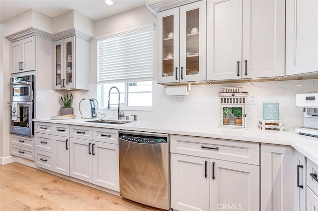 40365 Trenton Ct, Temecula, CA 92591 - kitchen featuring appliances with stainless steel finishes, light countertops, light wood-type flooring, glass insert cabinets, and recessed lighting