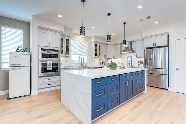 40365 Trenton Ct, Temecula, CA 92591 - kitchen with appliances with stainless steel finishes, wall chimney exhaust hood, light wood-style floors, a kitchen island, and recessed lighting