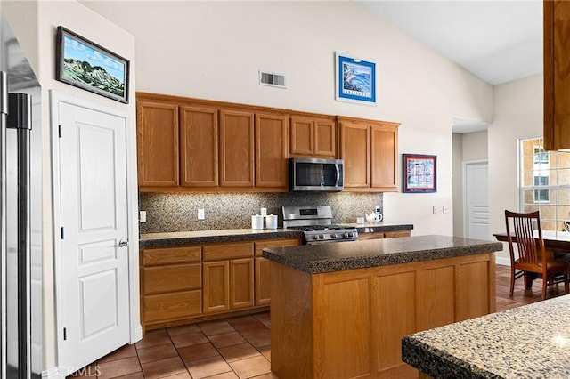 4802 Pentz Rd, Paradise, CA 95969 - kitchen featuring stainless steel appliances, backsplash, a kitchen island, brown cabinets, and high vaulted ceiling