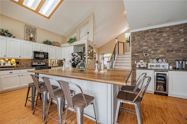 1122 Moonbeam Way, Turlock, CA 95382 - kitchen featuring wine cooler, black microwave, tasteful backsplash, white cabinets, and high vaulted ceiling