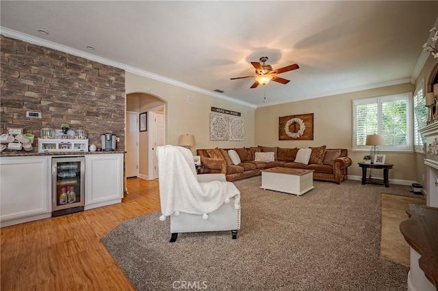 1122 Moonbeam Way, Turlock, CA 95382 - living room featuring beverage cooler, crown molding, a ceiling fan, light wood finished floors, and arched walkways