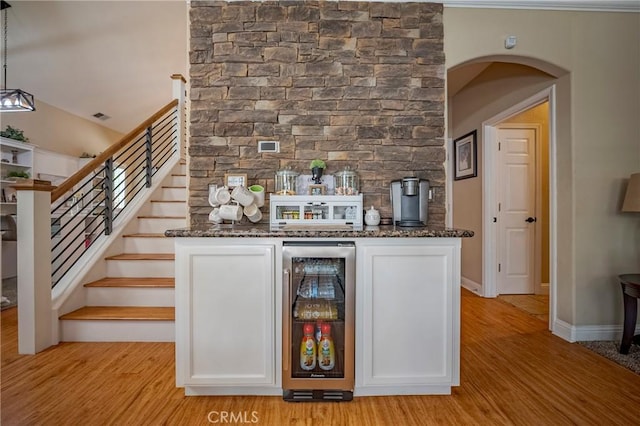 1122 Moonbeam Way, Turlock, CA 95382 - indoor dry bar featuring wine cooler, light wood-type flooring, arched walkways, stairway, and baseboards