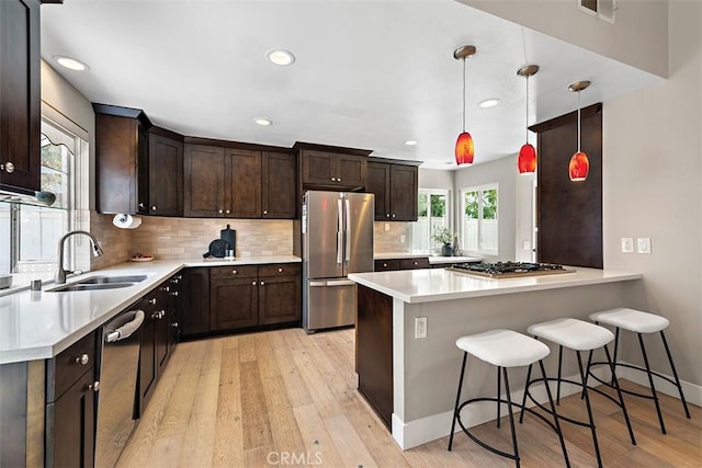 1890 Orange Ave, Costa Mesa, CA 92627 - kitchen with appliances with stainless steel finishes, dark brown cabinetry, light wood finished floors, light countertops, and backsplash