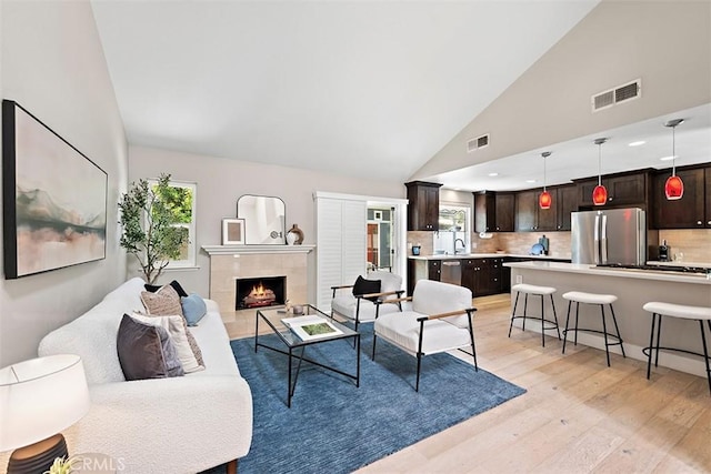 1890 Orange Ave, Costa Mesa, CA 92627 - living room with light wood-style flooring, high vaulted ceiling, and a tiled fireplace