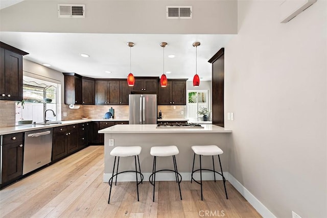 1890 Orange Ave, Costa Mesa, CA 92627 - kitchen with stainless steel appliances, a kitchen bar, tasteful backsplash, light wood-style flooring, and light countertops