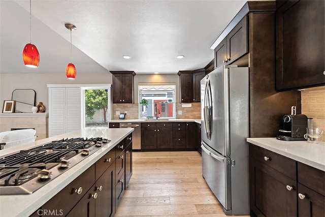 1890 Orange Ave, Costa Mesa, CA 92627 - kitchen with appliances with stainless steel finishes, dark brown cabinets, light countertops, light wood finished floors, and decorative light fixtures