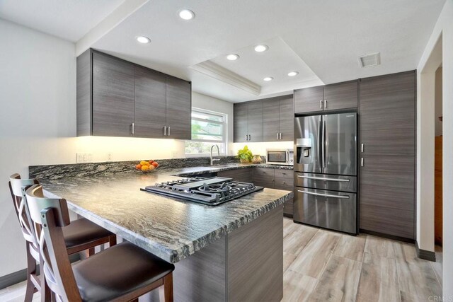 3332 Heather Ridge Ct, San Marcos, CA 92078 - kitchen with appliances with stainless steel finishes, a sink, a peninsula, a kitchen bar, and a tray ceiling