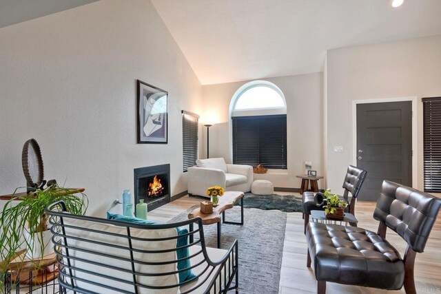 3332 Heather Ridge Ct, San Marcos, CA 92078 - living area with wood finished floors, vaulted ceiling, a warm lit fireplace, and baseboards