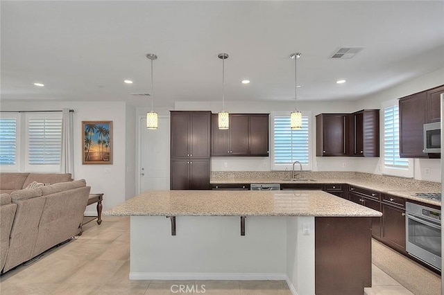 13029 Waterlily Way, Chino, CA 91710 - kitchen with appliances with stainless steel finishes, a center island, dark brown cabinetry, a kitchen bar, and recessed lighting