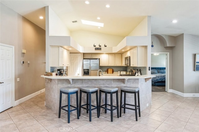 43300 Warner Trl, Palm Desert, CA 92211 - kitchen with stainless steel appliances, a kitchen bar, tasteful backsplash, recessed lighting, and high vaulted ceiling