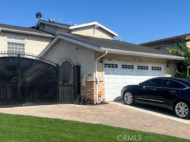 17506 Sandlake Ave, Carson, CA 90746 - view of side of property with an attached garage, decorative driveway, stucco siding, and a gate