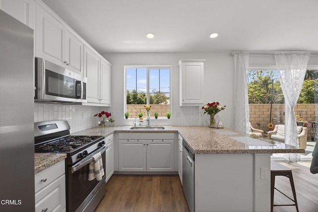 275 Fuerte Dr, Santa Paula, CA 93060 - kitchen with stainless steel appliances, a peninsula, decorative backsplash, white cabinetry, and recessed lighting
