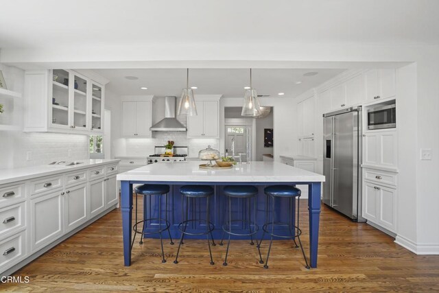 1550 Scenic Dr, Pasadena, CA 91103 - kitchen featuring appliances with stainless steel finishes, wall chimney range hood, a breakfast bar area, white cabinets, and recessed lighting