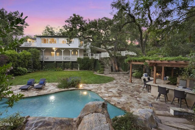 1550 Scenic Dr, Pasadena, CA 91103 - back of house at dusk featuring a pergola, a lawn, a patio, and an outdoor pool