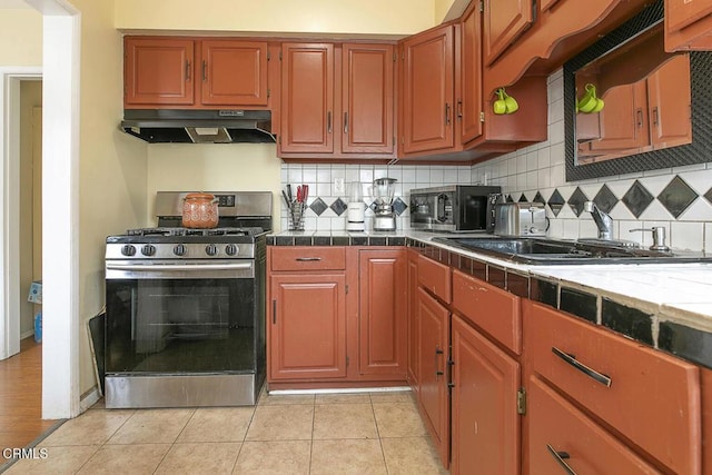 15207 Lorne St, Panorama City, CA 91402 - kitchen featuring under cabinet range hood, stainless steel range with gas stovetop, black microwave, and backsplash