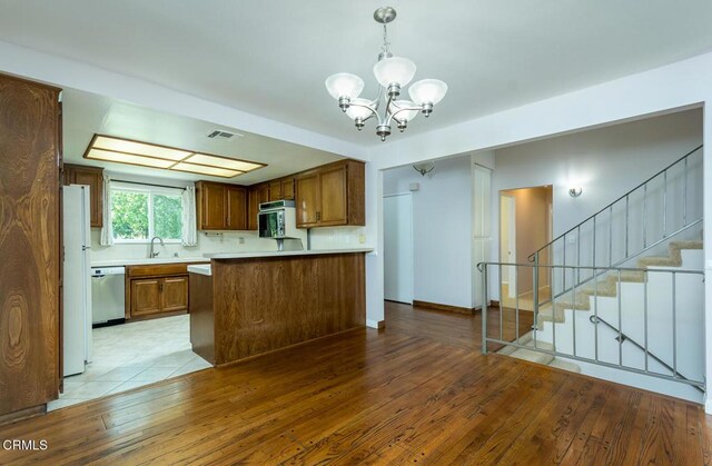 13807 Bradley Ave, Sylmar, CA 91342 - kitchen with dishwasher, a chandelier, light countertops, light wood-style floors, and brown cabinetry