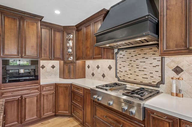525 Hilo Way, Vista, CA 92081 - kitchen featuring premium range hood, stainless steel gas stovetop, light countertops, decorative backsplash, and glass insert cabinets