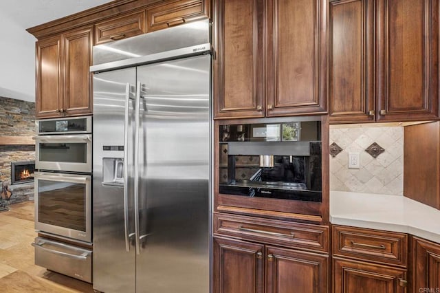 525 Hilo Way, Vista, CA 92081 - kitchen with stainless steel appliances, a warming drawer, tasteful backsplash, a fireplace, and light countertops