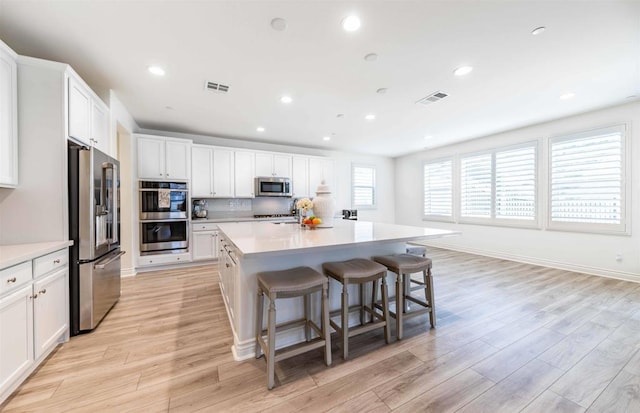 35909 Shetland Hls E, Fallbrook, CA 92028 - kitchen with stainless steel appliances, white cabinets, recessed lighting, a center island, and light wood-style flooring