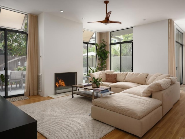 265 Coast Blvd Unit 9, La Jolla, CA 92037 - living room featuring expansive windows, ceiling fan, a lit fireplace, wood finished floors, and recessed lighting