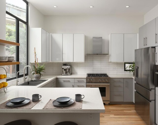 265 Coast Blvd Unit 9, La Jolla, CA 92037 - kitchen featuring appliances with stainless steel finishes, wall chimney range hood, gray cabinets, light countertops, and recessed lighting