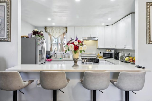 1947 D Ave, National City, CA 91950 - kitchen with stainless steel appliances, under cabinet range hood, white cabinetry, a peninsula, and recessed lighting
