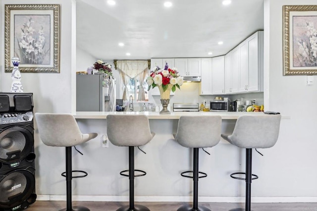 1947 D Ave, National City, CA 91950 - kitchen with stainless steel appliances, a peninsula, recessed lighting, white cabinetry, and under cabinet range hood