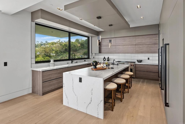 6627 Muirlands Dr, La Jolla, CA 92037 - kitchen featuring stainless steel range, modern cabinets, a kitchen island, a kitchen bar, and decorative backsplash