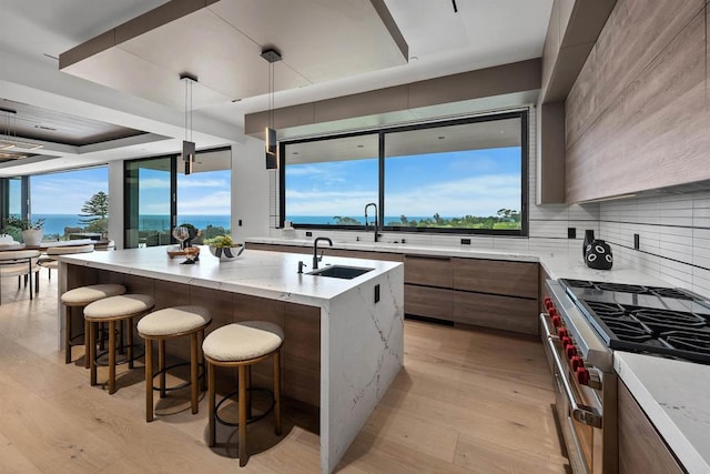 6627 Muirlands Dr, La Jolla, CA 92037 - kitchen with modern cabinets, high end stainless steel range oven, light wood finished floors, a kitchen breakfast bar, and light stone counters