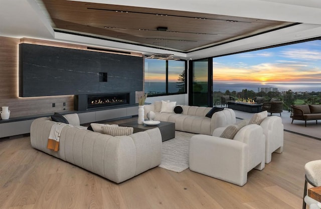 6627 Muirlands Dr, La Jolla, CA 92037 - living area with wood finished floors, a lit fireplace, floor to ceiling windows, wood ceiling, and a raised ceiling