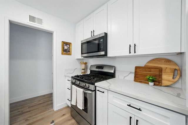 1472 Loma Ln, Chula Vista, CA 91911 - kitchen with stainless steel appliances, light stone counters, light wood-type flooring, and white cabinetry