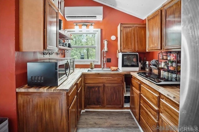 22230 Crestline Rd, Palomar Mountain, CA 92060 - kitchen with stainless steel appliances, a wall unit AC, brown cabinets, vaulted ceiling, and dark wood finished floors