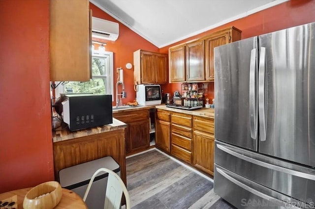 22230 Crestline Rd, Palomar Mountain, CA 92060 - kitchen with freestanding refrigerator, a wall mounted AC, vaulted ceiling, brown cabinetry, and light countertops
