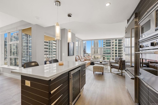 1325 Pacific Hwy Unit 1004, San Diego, CA 92101 - kitchen featuring appliances with stainless steel finishes, beverage cooler, a city view, light wood-type flooring, and dark brown cabinets