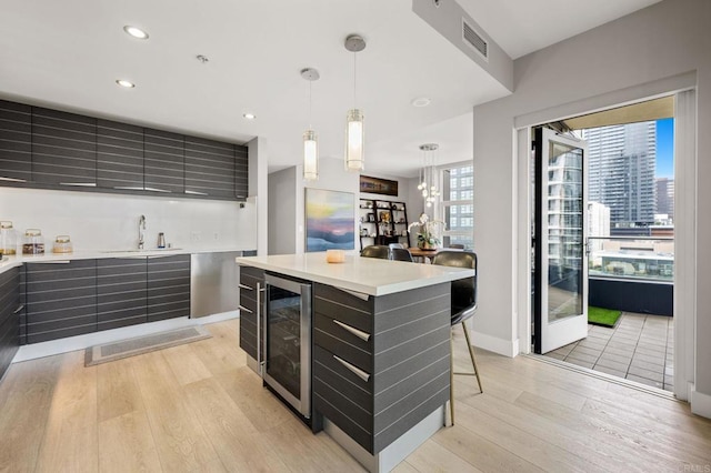 1325 Pacific Hwy Unit 1004, San Diego, CA 92101 - kitchen with beverage cooler, modern cabinets, light wood-style flooring, light countertops, and pendant lighting