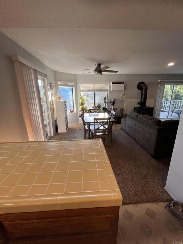 8606 Valley View Trl, Pine Valley, CA 91962 - living area with carpet floors, a wood stove, a wall mounted AC, and a ceiling fan