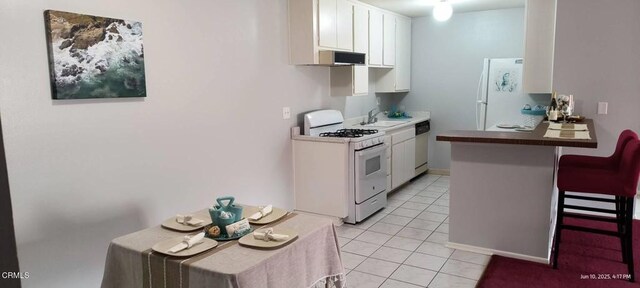 247 W Channel Islands Blvd, Port Hueneme, CA 93041 - kitchen featuring white appliances, white cabinets, a kitchen breakfast bar, light tile patterned flooring, and extractor fan
