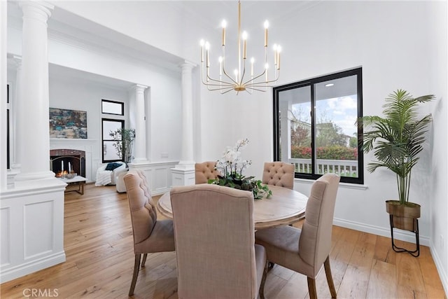 23 Fawnridge Pl, Aliso Viejo, CA 92656 - dining area featuring light wood-style floors, ornate columns, a chandelier, a lit fireplace, and crown molding