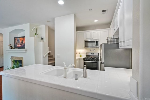 4049 Peninsula Dr, Carlsbad, CA 92010 - kitchen featuring stainless steel appliances, tile countertops, white cabinetry, recessed lighting, and a fireplace