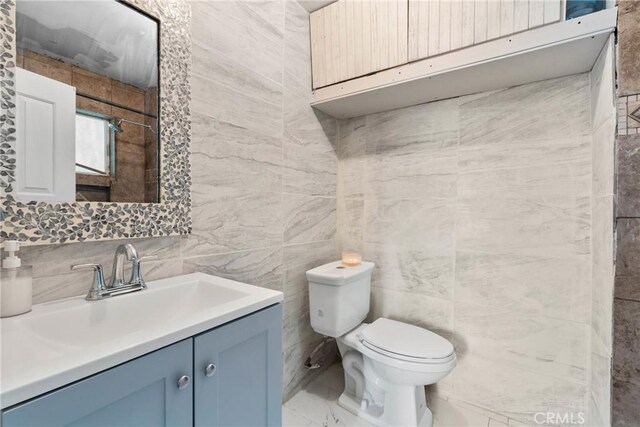 671 N Cherry St, Banning, CA 92220 - bathroom featuring toilet, vanity, and tile walls