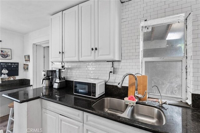 671 N Cherry St, Banning, CA 92220 - kitchen featuring a sink, white cabinets, decorative backsplash, and dark stone counters