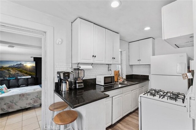 671 N Cherry St, Banning, CA 92220 - kitchen featuring white appliances, white cabinetry, decorative backsplash, recessed lighting, and a kitchen breakfast bar